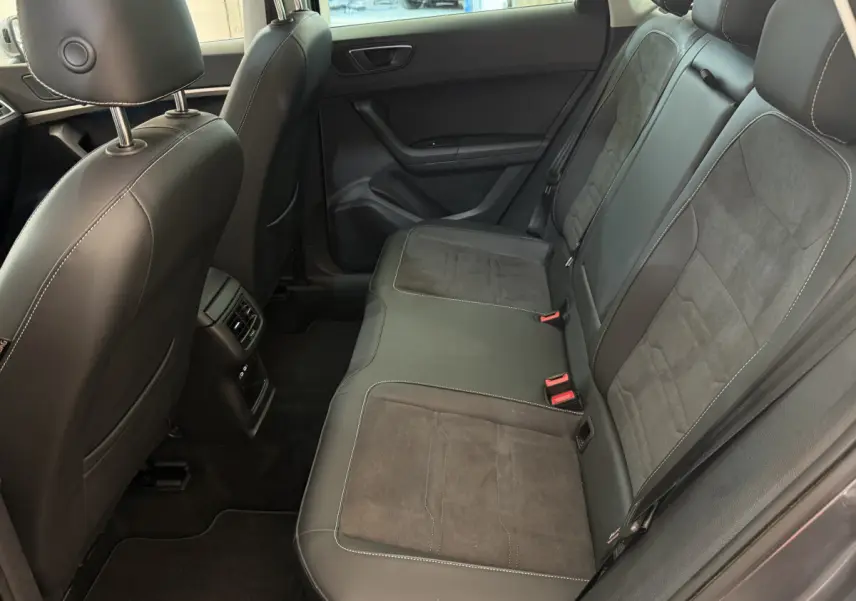 Vue intérieure côté droit des sièges arrière en cuir noir du SEAT Ateca gris clair 2023 avec appuis-tête et ceintures visibles.
