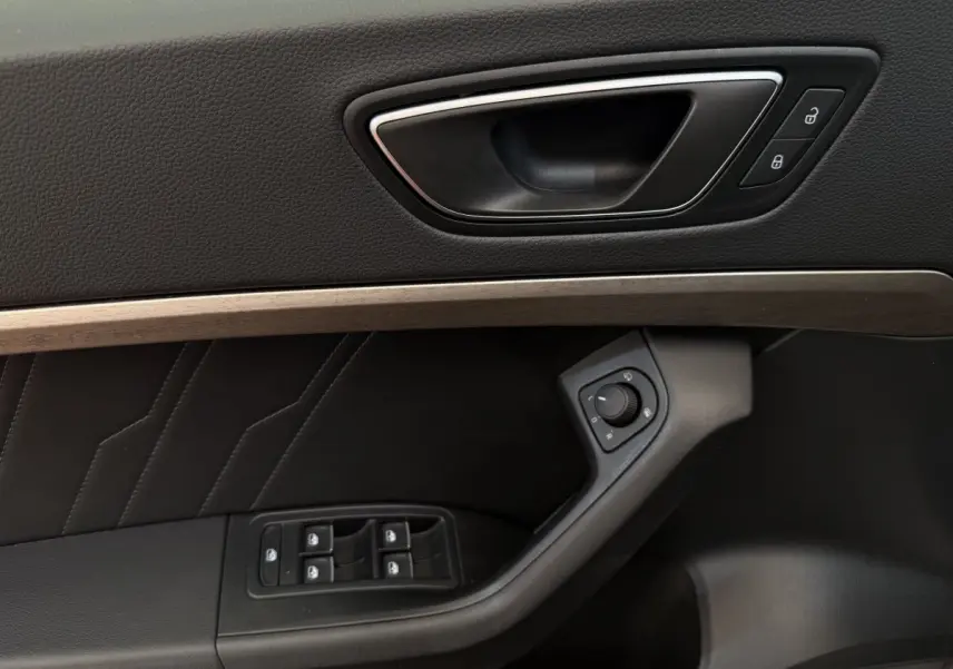 Détail de la porte côté conducteur du SEAT Ateca gris clair 2023 avec commandes électriques et habillage noir.