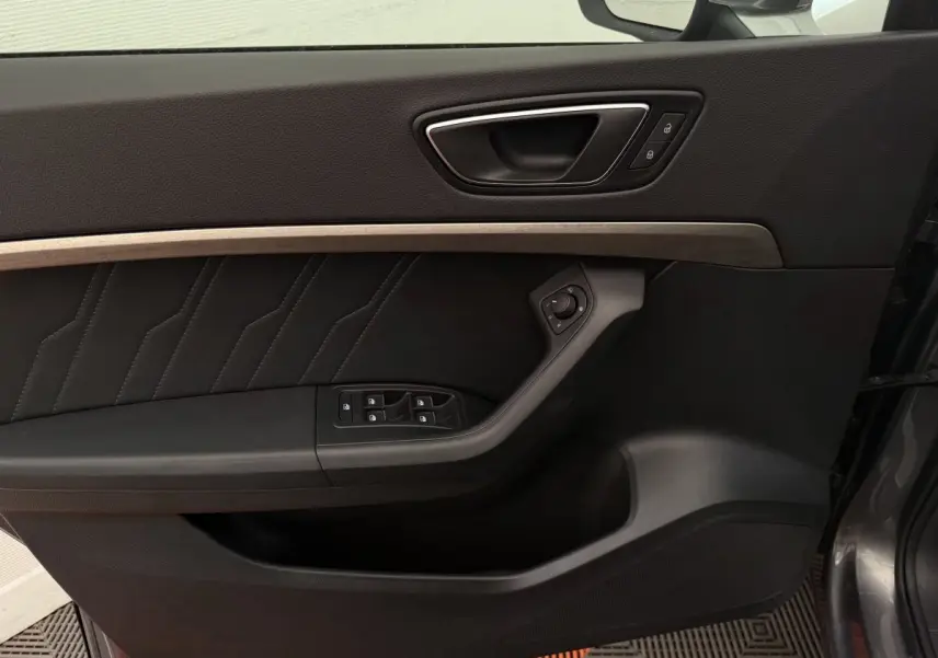 Porte intérieure côté gauche du SEAT Ateca gris clair, avec commandes électriques et insert décoratif bois.