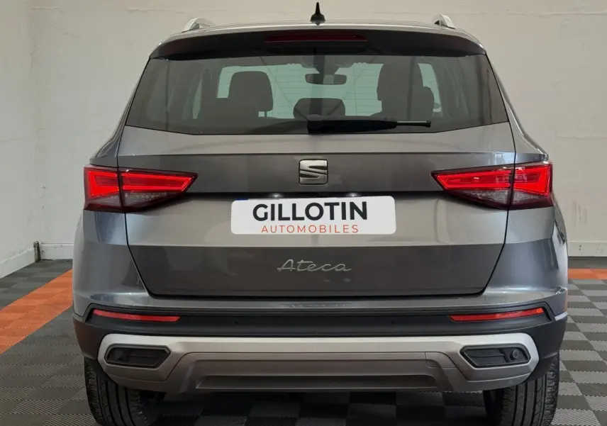 Vue arrière d'un SEAT Ateca gris clair 2023 avec feux LED et double sortie d'échappement intégrée.