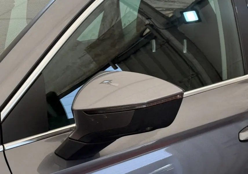 Rétroviseur côté gauche gris clair du SEAT Ateca 2023 avec clignotant intégré, vue rapprochée sur porte et vitre.