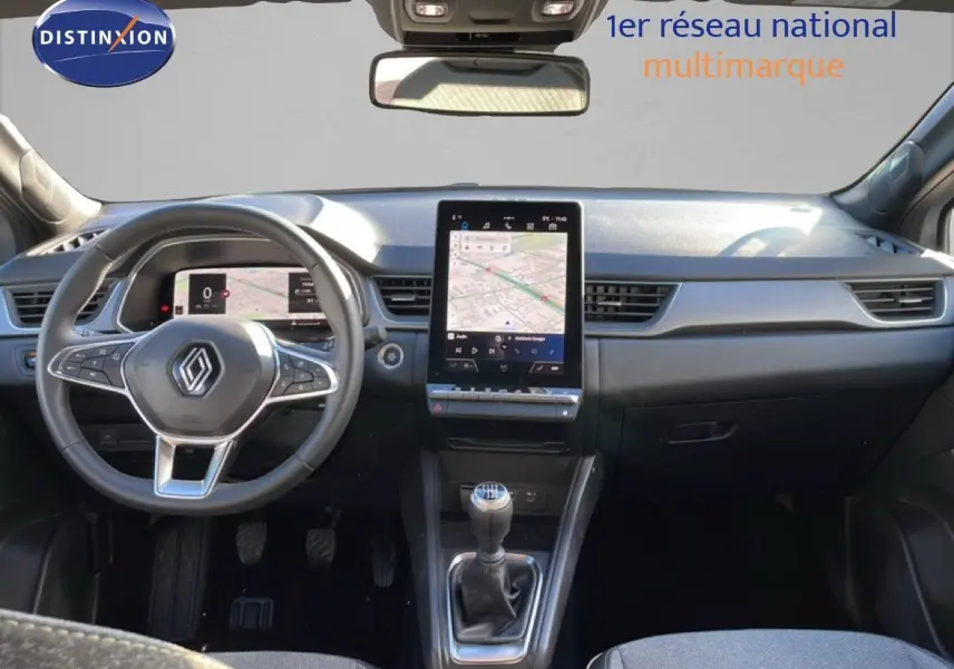 Vue intérieure avant du Renault Captur 2025 gris rafale, avec tableau de bord numérique et écran tactile central vertical.