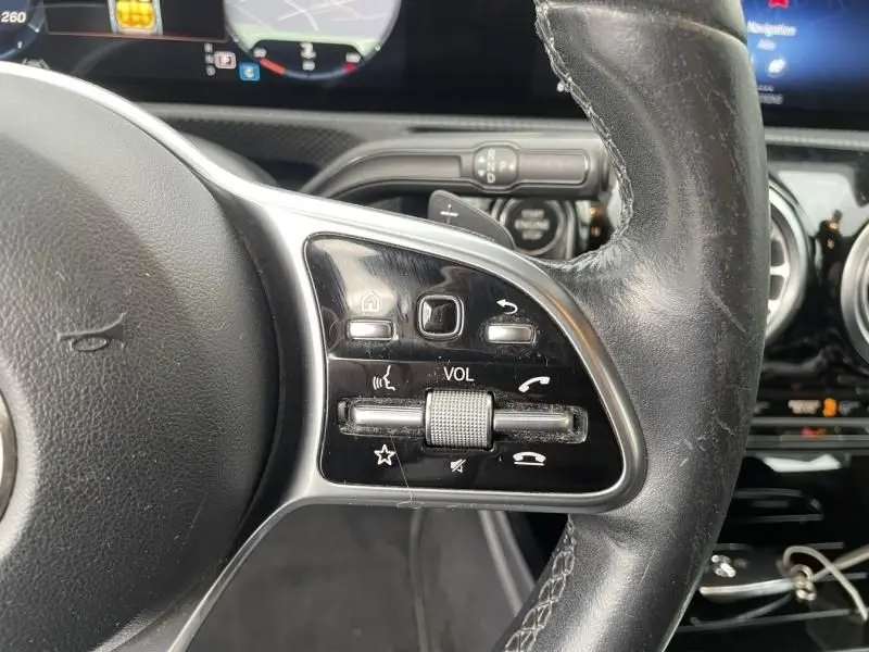 Gros plan sur les commandes au volant à droite d’une Mercedes Classe A 2019, finition Progressive Line, avec boutons multifonctions.