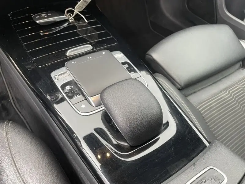 Vue rapprochée de la console centrale noire brillante avec le levier de vitesse et le pavé tactile d'une Mercedes Classe A 2019.