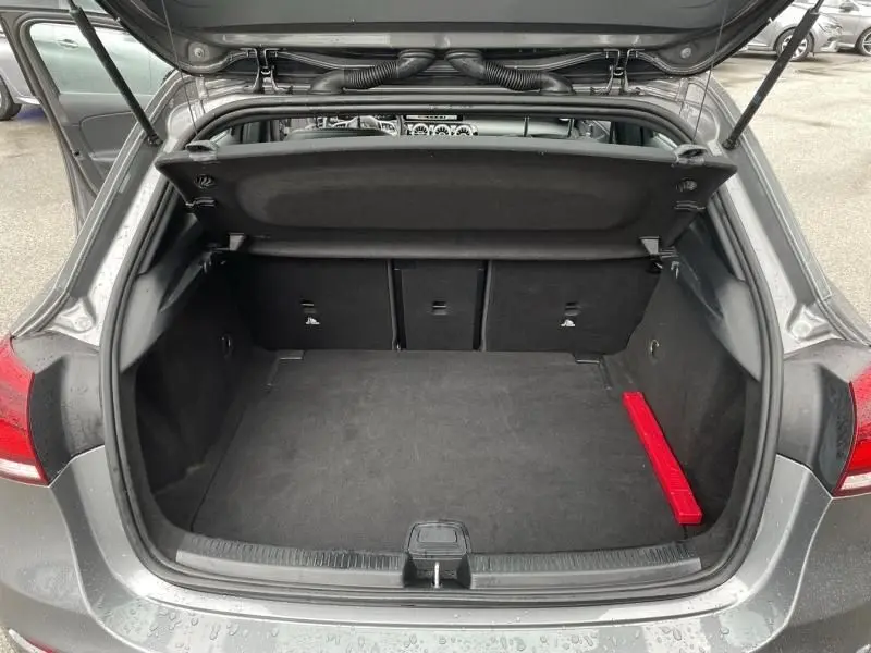 Coffre ouvert vu de l'arrière d'une Mercedes Classe A 200 gris foncé métal, montrant un espace de chargement propre et un triangle de sécurité rouge.