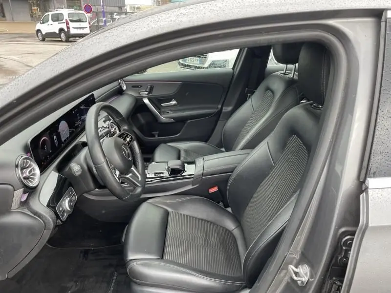 Vue intérieure côté conducteur d'une Mercedes Classe A 200 gris foncé métal, sièges cuir et tableau de bord numérique.