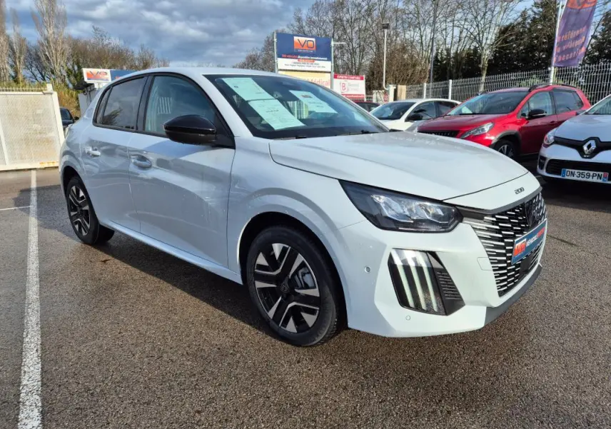 Peugeot 208 Hybrid blanc vue 3/4 avant droit, jantes alliage 16 pouces et feux diurnes verticaux visibles.