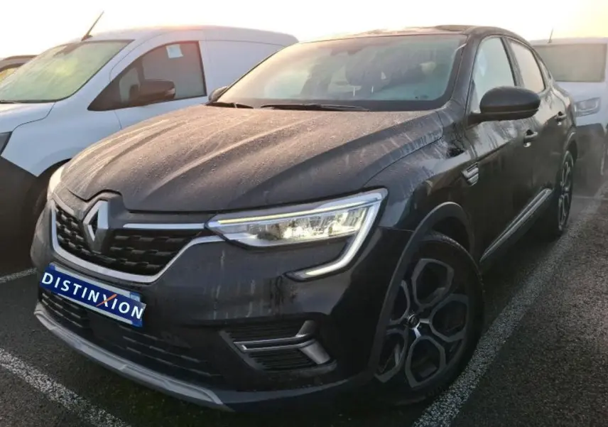 Renault Arkana 1.6 E-Tech hybride noir métal vu en 3/4 avant droit, avec feux allumés et jantes spécifiques.