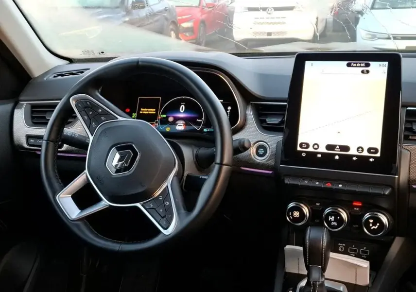 Vue intérieure du tableau de bord et volant de la Renault Arkana 1.6 E-Tech hybride 2023 avec écran tactile vertical et commandes au volant.