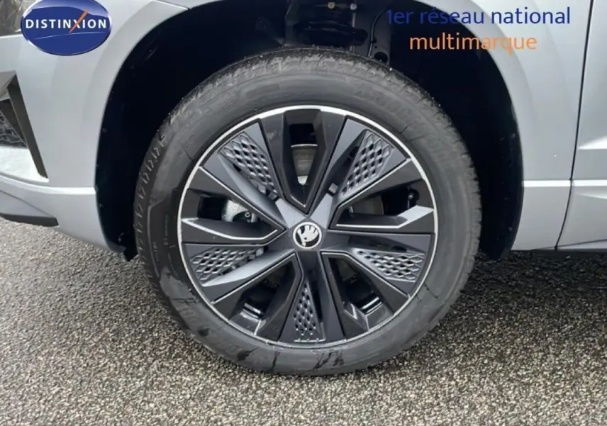 Gros plan sur la roue avant droite d’un Skoda Karoq argent 2025 avec jante noire au design moderne.