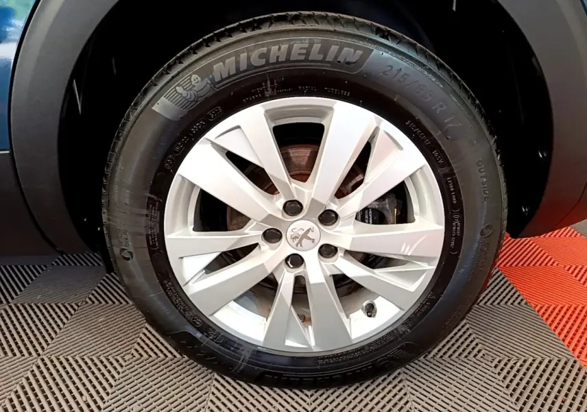 Gros plan sur la roue avant droite d’un Peugeot 5008 bleu avec jante alliage et pneu Michelin.