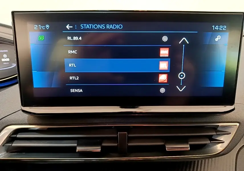 Écran tactile central affichant les stations radio dans l’habitacle d’un Peugeot 5008 bleu, vue de face.