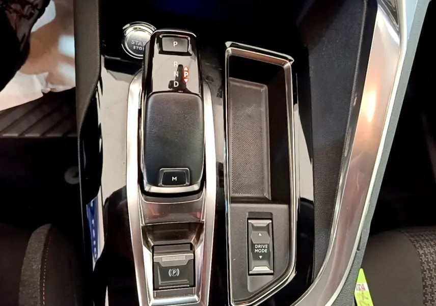 Vue rapprochée de la console centrale noire brillante du Peugeot 5008 avec levier de boîte automatique et bouton Drive Mode.