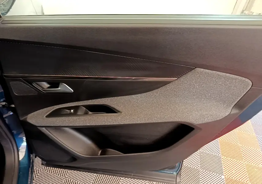 Vue intérieure de la porte avant gauche d’un Peugeot 5008 bleu, avec garniture tissu et plastique noir.