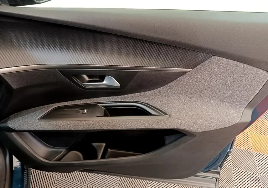 Vue intérieure côté gauche de la porte avant d’un Peugeot 5008 bleu, avec habillage tissu et poignée argentée.