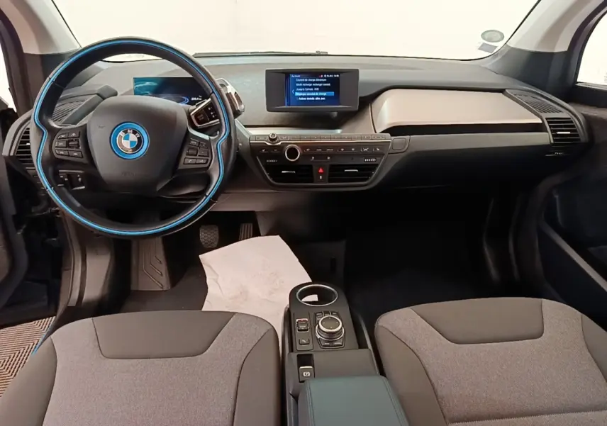 Intérieur avant de BMW i3 120 Ah noir, vue centrée sur le tableau de bord et le volant multifonction avec détails bleus.