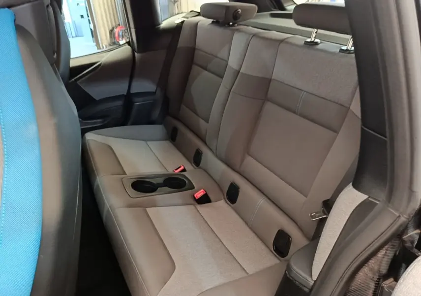 Vue intérieure arrière droite sur la banquette sport grise du BMW i3 120 Ah Atelier avec accoudoir central et porte-gobelets.