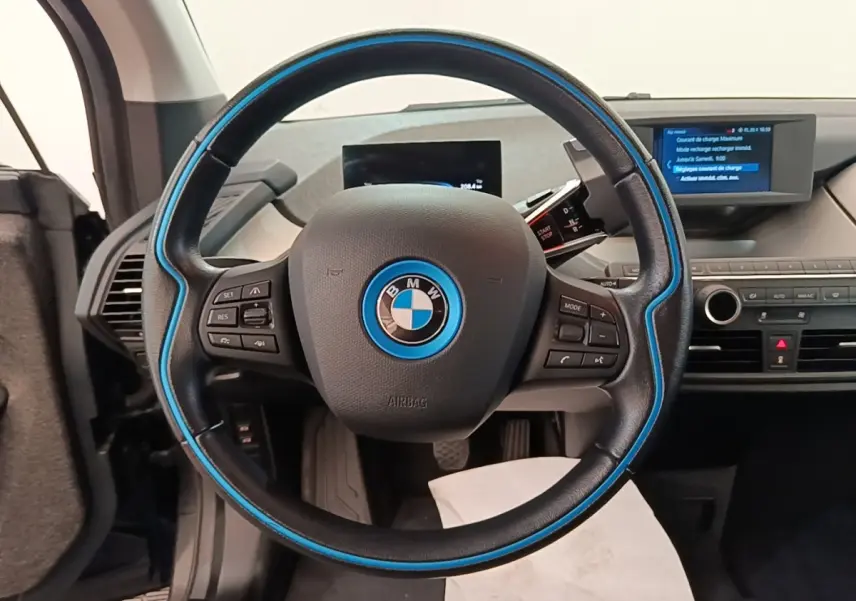 Vue intérieure centrée sur le volant noir avec liseré bleu de la BMW i3 120 Ah Atelier de 2020.