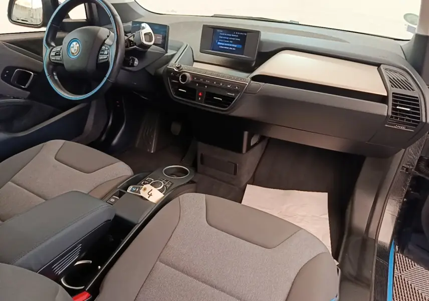 Vue intérieure côté conducteur de la BMW i3 120 Ah noire, avec tableau de bord digital et volant cuir multifonctions.