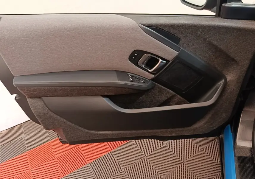 Gros plan sur la porte intérieure côté gauche de la BMW i3 120 Ah Atelier noire, montrant les commandes et le revêtement tissu.