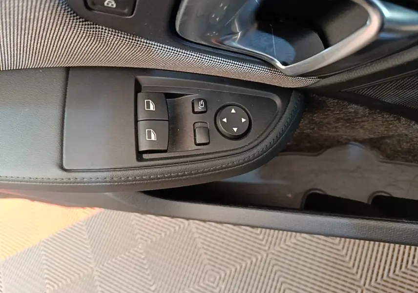 Vue rapprochée du panneau de commandes des vitres côté gauche intérieur d’une BMW i3 noire 2020.