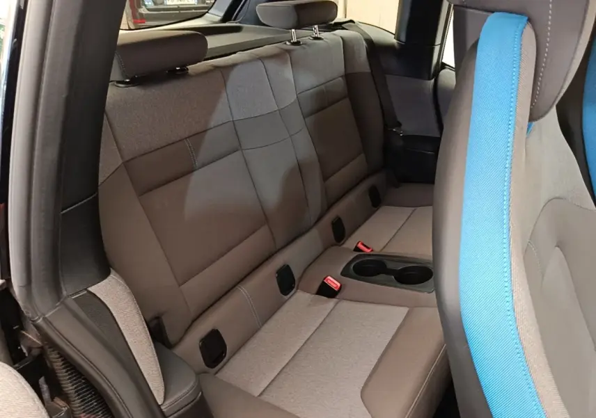 Vue intérieure côté arrière droit de la BMW i3 120 Ah noire, montrant la banquette arrière grise avec porte-gobelets central.