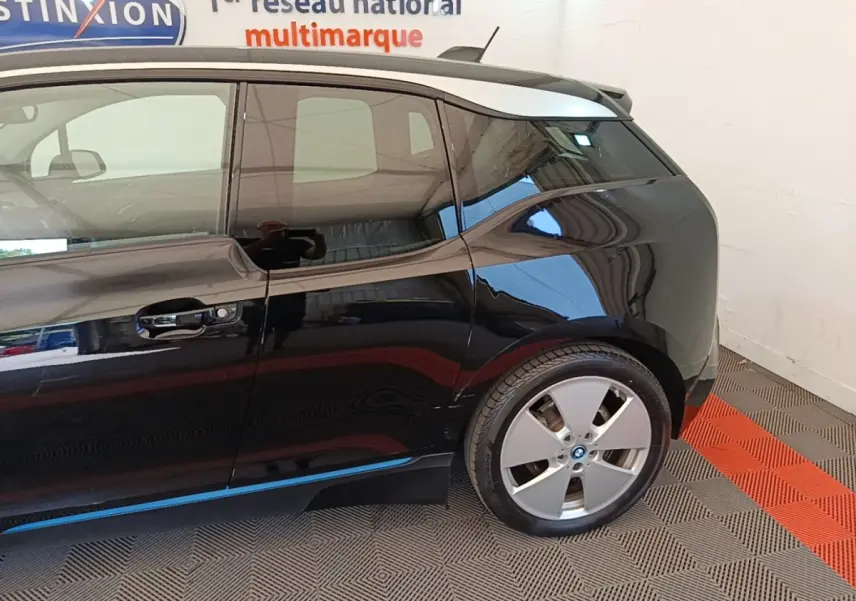 Vue latérale côté droit d'une BMW i3 120 Ah Atelier noire, mettant en valeur la porte arrière et la roue arrière.