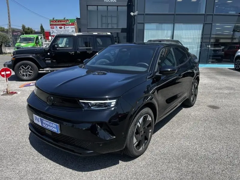 Opel Mokka Electric 156 GS noir vue 3/4 avant droit, avec calandre lisse et jantes spécifiques électriques.