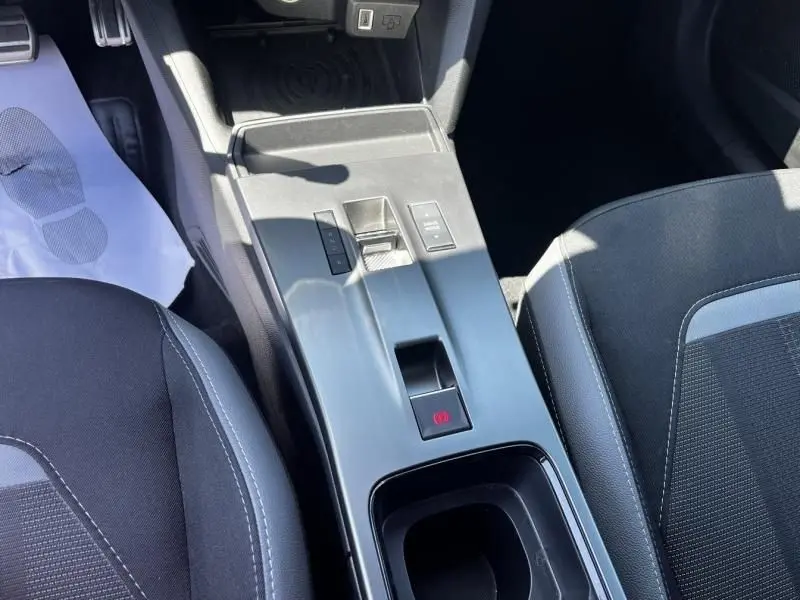 Vue plongeante sur la console centrale noire de l'Opel Mokka Electric 156 GS 2025, avec frein à main électronique et sièges tissu.