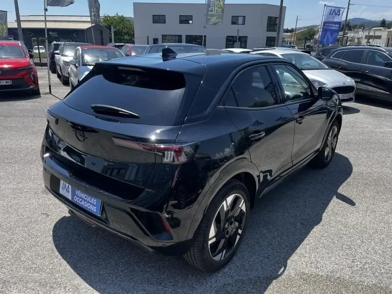 Vue 3/4 arrière droite d'un Opel Mokka Electric 156 GS noir brillant, avec jantes modernes et vitres teintées.