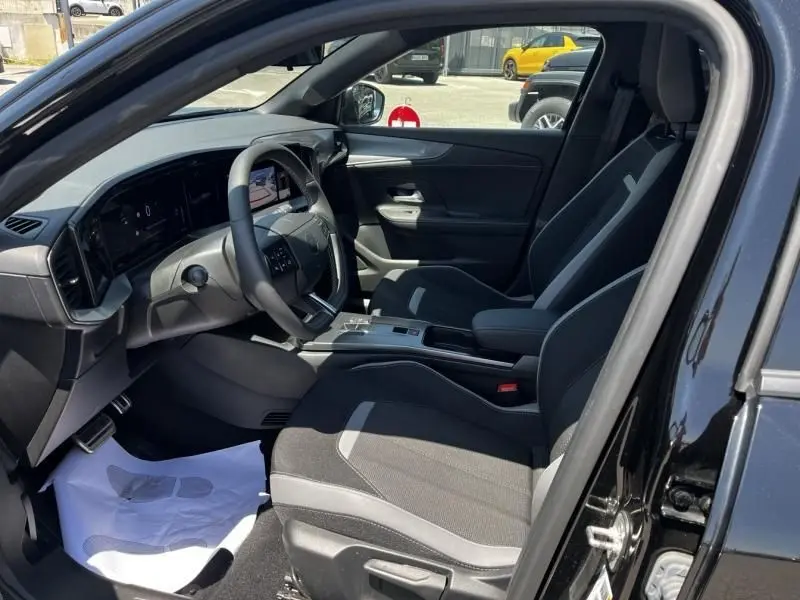 Vue intérieure côté conducteur de l’Opel Mokka Electric 156 GS 2025 noir, avec tableau de bord digital et sièges tissu gris.