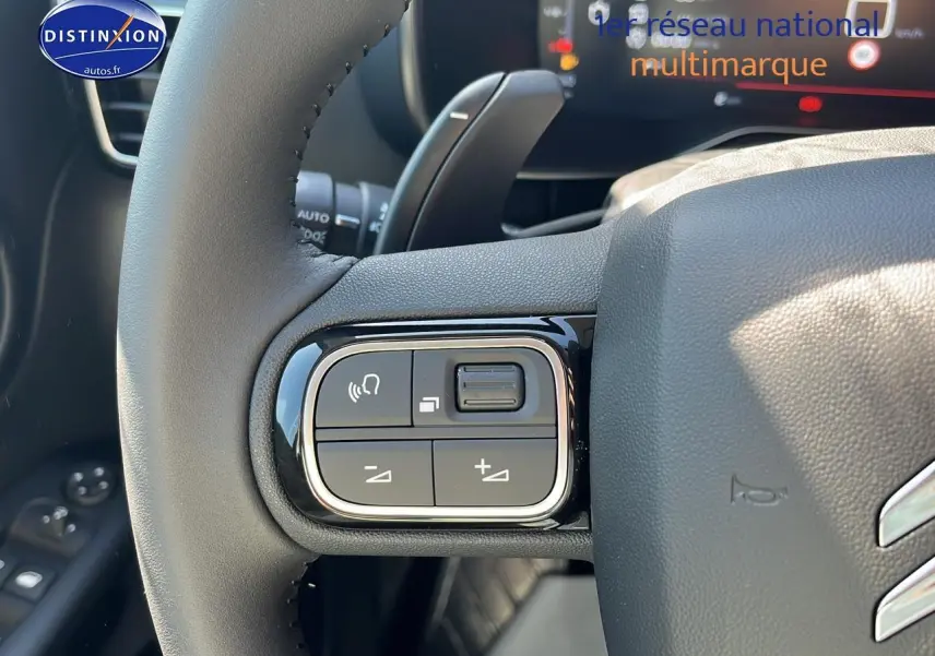 Gros plan sur les commandes gauche du volant du Citroën C5 Aircross 2025 noir, avec tableau de bord digital en arrière-plan.