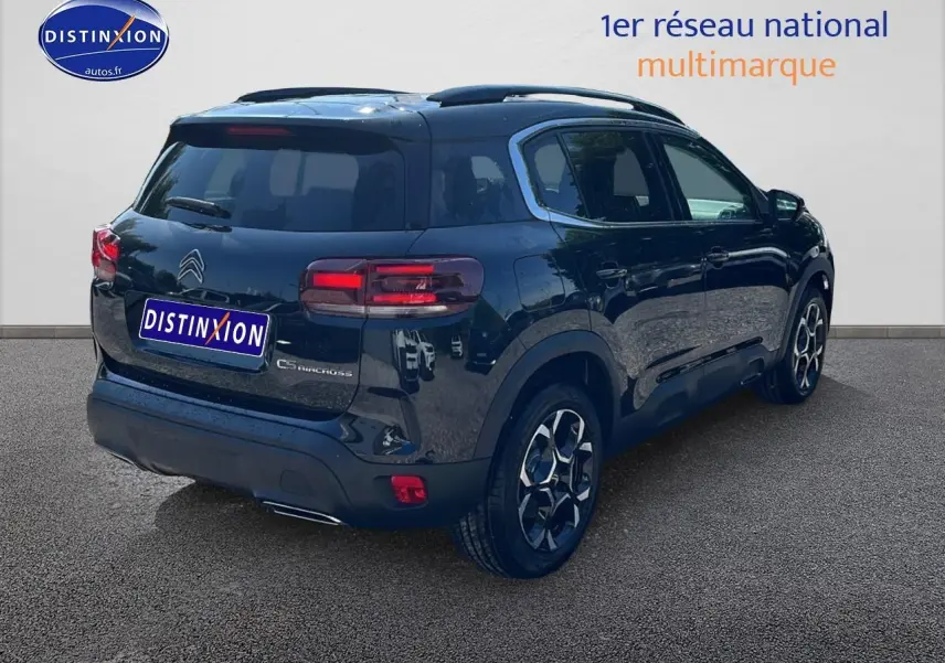 Vue 3/4 arrière droite d'un Citroën C5 Aircross noir avec toit bi-ton et jantes alu 18 pouces sur sol gris.