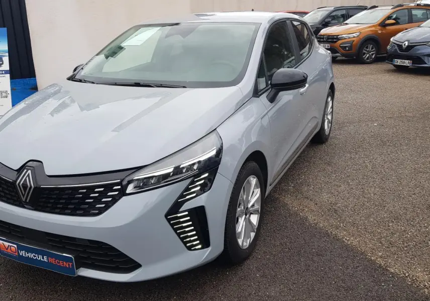 Renault Clio gris vue 3/4 avant droit, avec signature lumineuse LED distinctive et calandre noire.