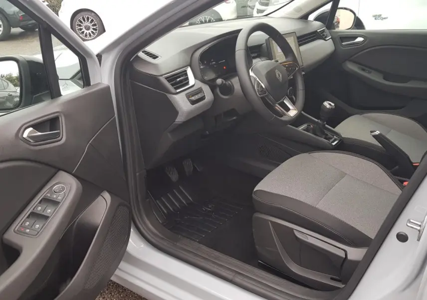 Intérieur côté conducteur de la Renault Clio gris 2025, vue sur tableau de bord, volant et sièges tissu bicolore.