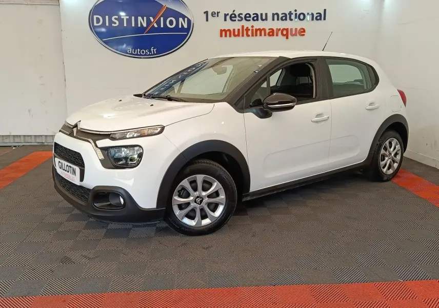 Citroën C3 blanche vue 3/4 avant droit en intérieur, avec phares LED et jantes alliage distinctives.