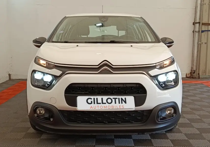 Vue avant d'une Citroën C3 blanche de 2022 avec phares LED allumés dans un garage.