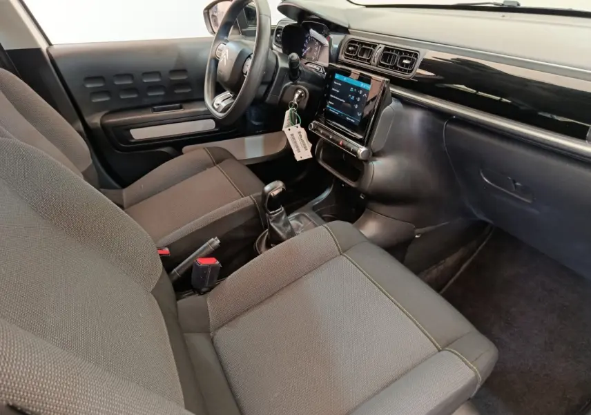 Intérieur de la Citroën C3 2022 vu côté conducteur, sièges gris, volant multifonctions et écran tactile central.