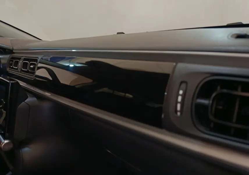 Vue rapprochée de la planche de bord noire brillante côté passager dans une Citroën C3 blanche 2022.