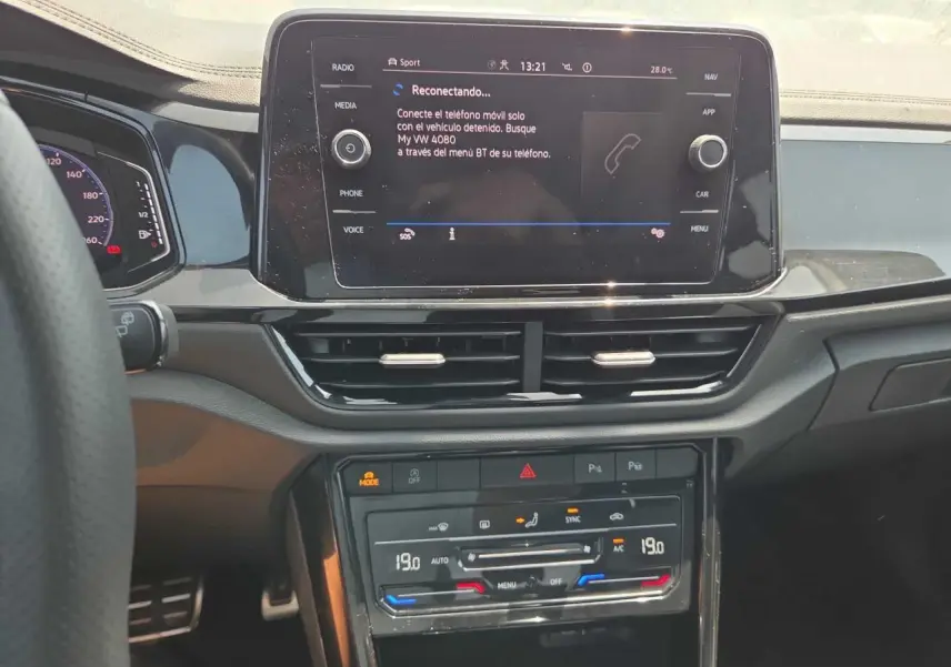 Vue rapprochée du tableau de bord noir brillant du Volkswagen T-Roc 2025 avec écran tactile et commandes climatisation digitales.