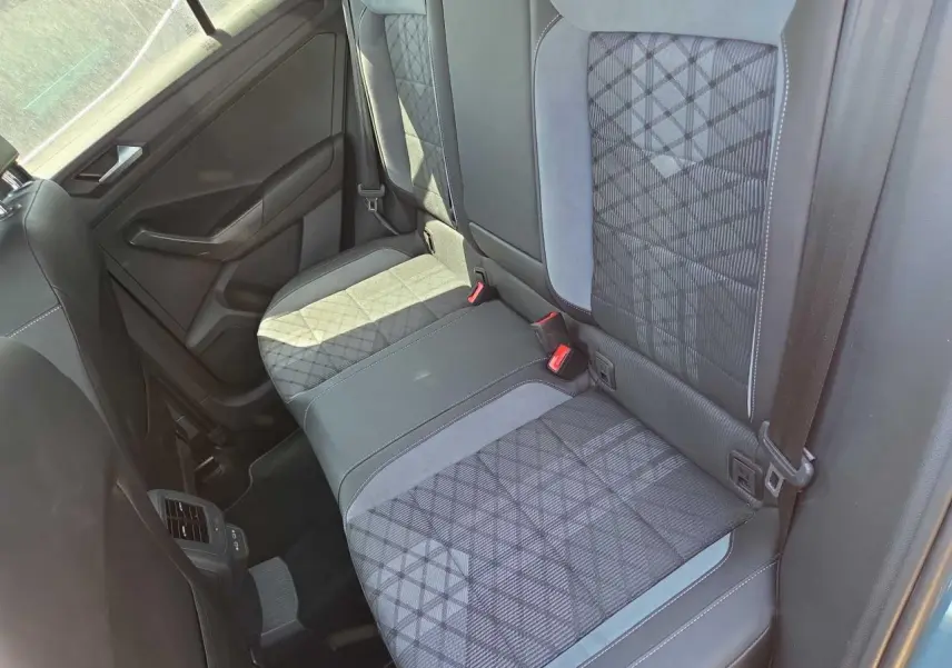 Vue intérieure de la banquette arrière du Volkswagen T-Roc 2025, tissu gris à motifs géométriques et ceintures visibles.
