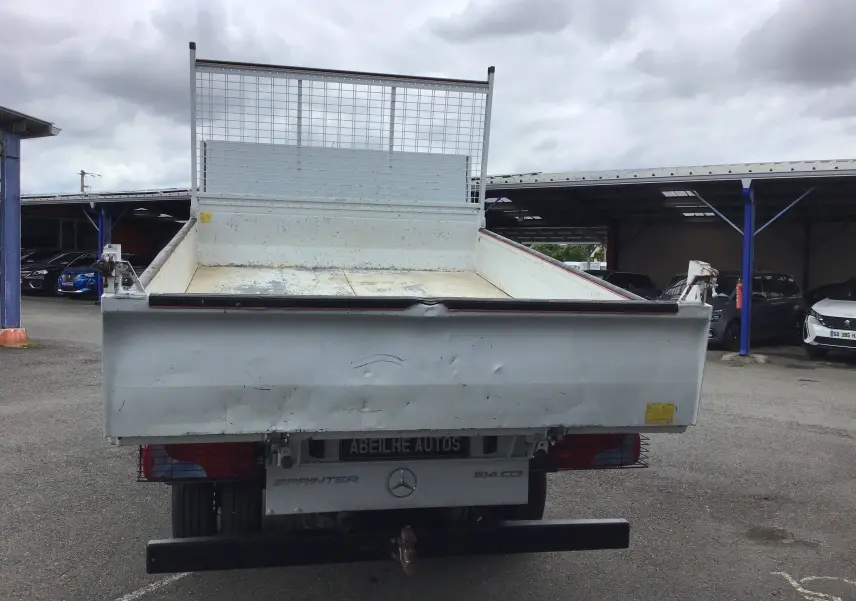 Vue arrière d'un utilitaire Mercedes Sprinter blanc avec benne 3 mètres et coffre, plateau ouvert et ridelles métalliques.