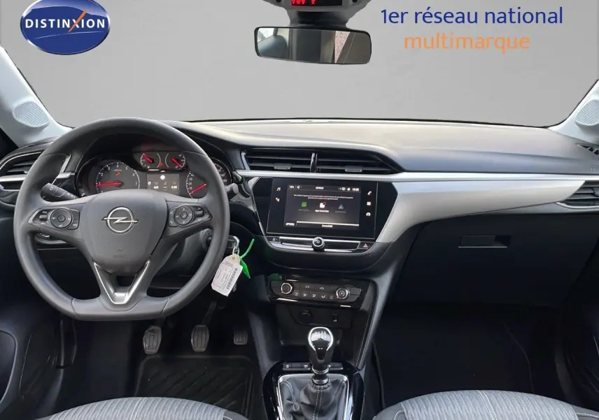 Vue intérieure avant de l'Opel Corsa 2022, tableau de bord noir et gris avec volant multifonction et levier de vitesse manuel.