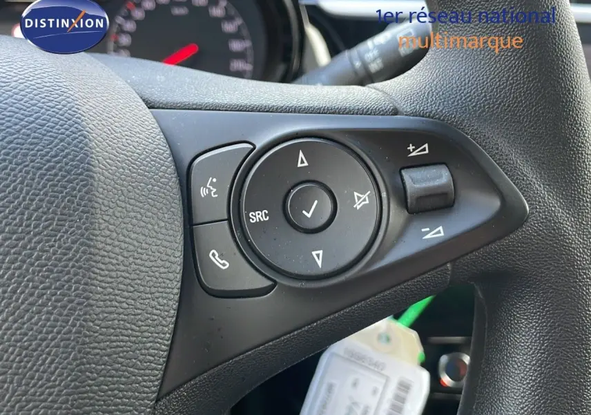 Gros plan sur les commandes multifonctions à gauche du volant en cuir noir d'une Opel Corsa gris Kristall Metal.