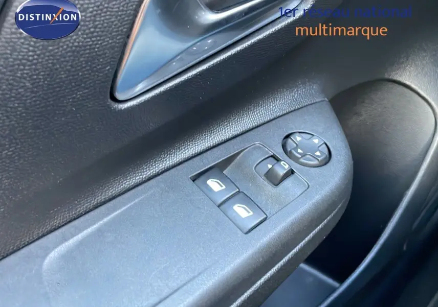 Gros plan sur les commandes de lève-vitres et réglage des rétroviseurs côté conducteur d'une Opel Corsa gris Kristall Metal.