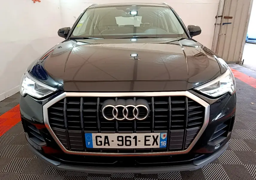 Vue frontale d'un Audi Q3 noir 35 TDI 150 S tronic Business Line avec calandre hexagonale et phares LED allumés.