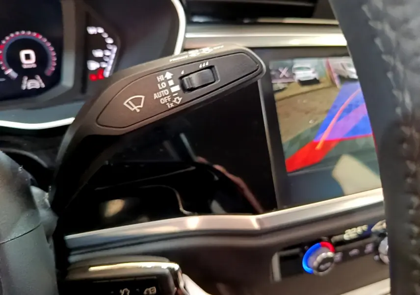 Gros plan sur la commande d'essuie-glace et l'écran de caméra de recul du tableau de bord d'un Audi Q3 noir.
