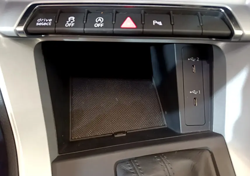Gros plan sur la console centrale noire de l'Audi Q3 35 TDI 2021 avec ports USB et boutons de contrôle au-dessus.