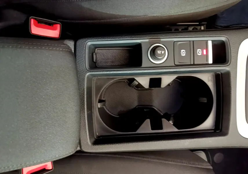 Gros plan sur la console centrale noire de l'Audi Q3 35 TDI 2021 avec porte-gobelets et prise 12V visible