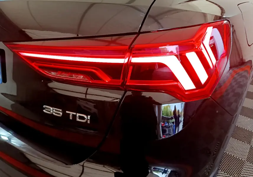 Gros plan sur le feu arrière droit rouge et l’inscription 35 TDI du coffre noir d’un Audi Q3 2021.